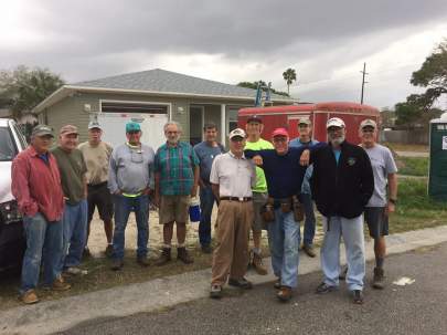 A group of volunteers in front of a new home in the final stages of building